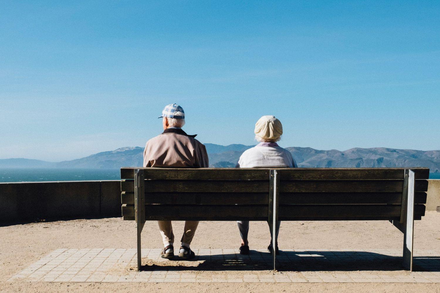 Zwei alte Menschen, die auf einer Bank im Freien sitzen