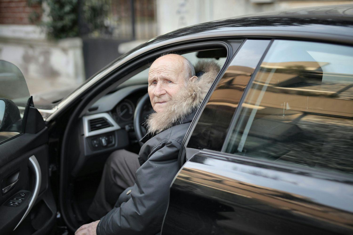 Ein alter schwerhöriger Mann mit Demenz sitzt im Auto