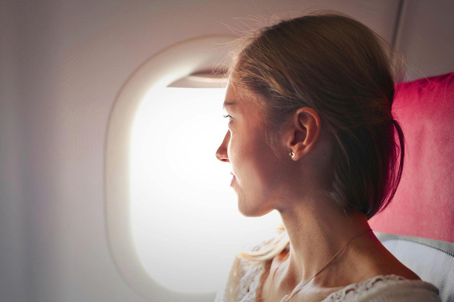 Eine Frau sitzt im Flugzeug und schaut aus dem Fenster