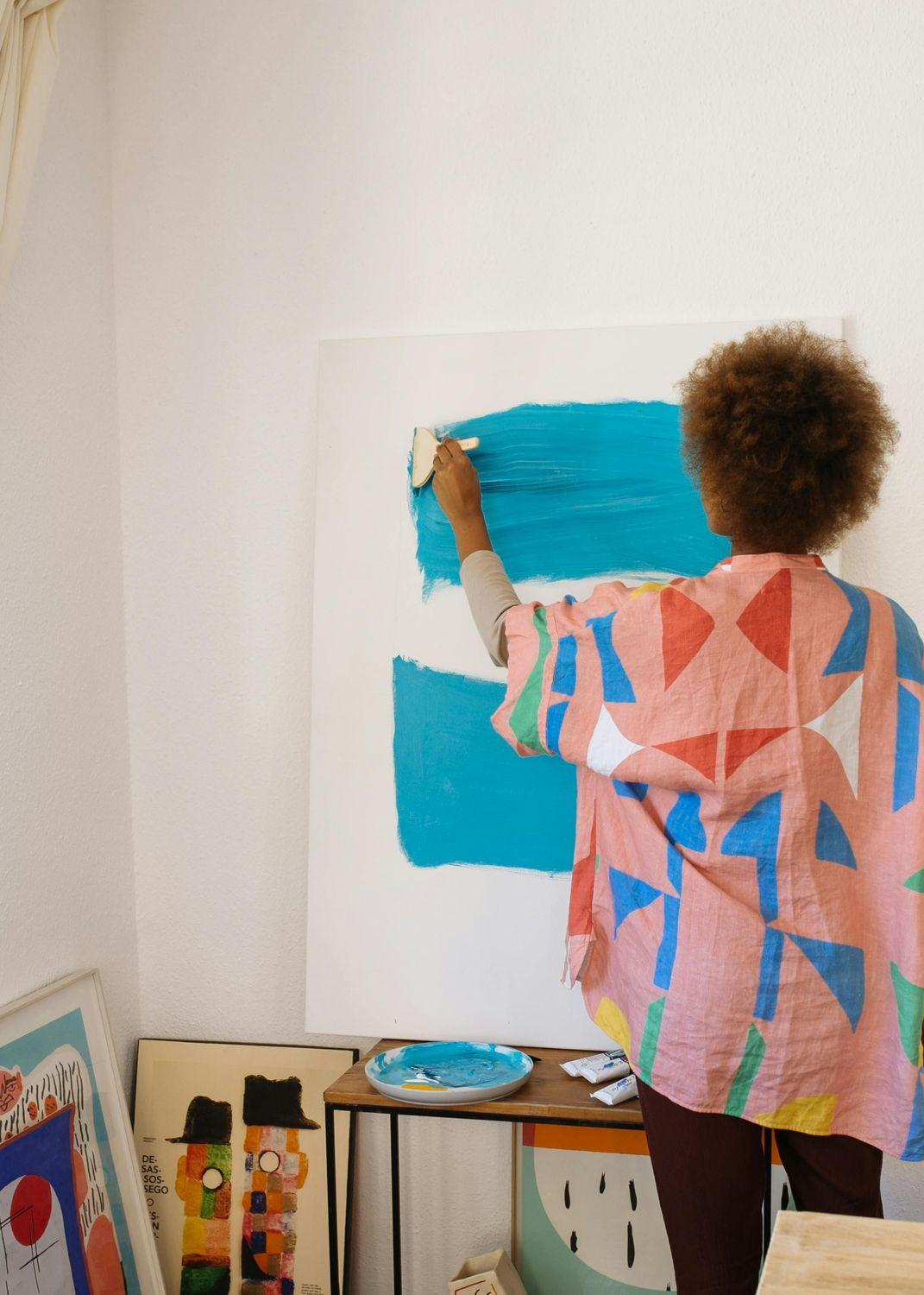 Eine Frau malt mit blauer Farbe auf eine Leinwand