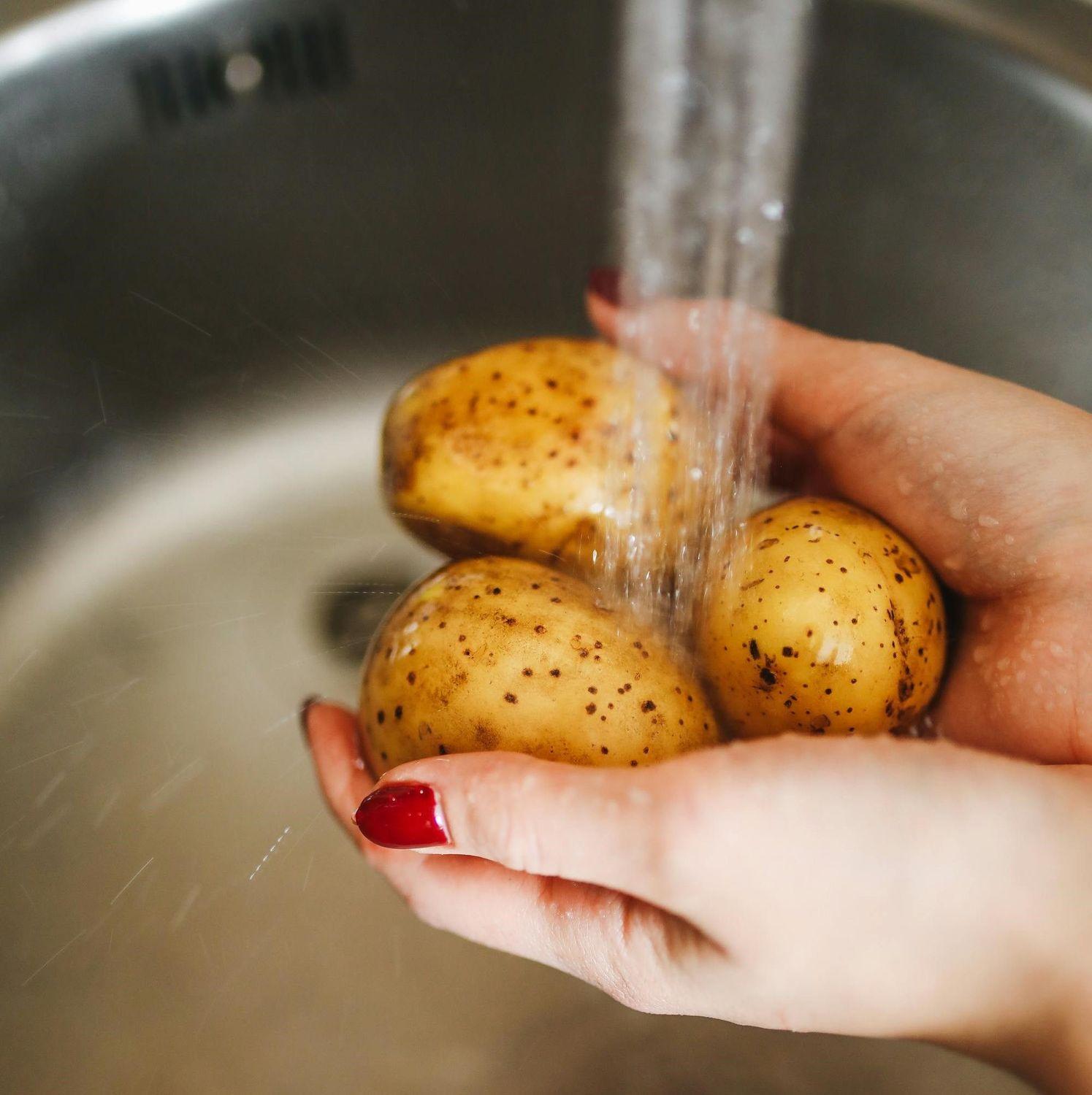 Kartoffeln, die per Hand mit Wasser gewaschen werden