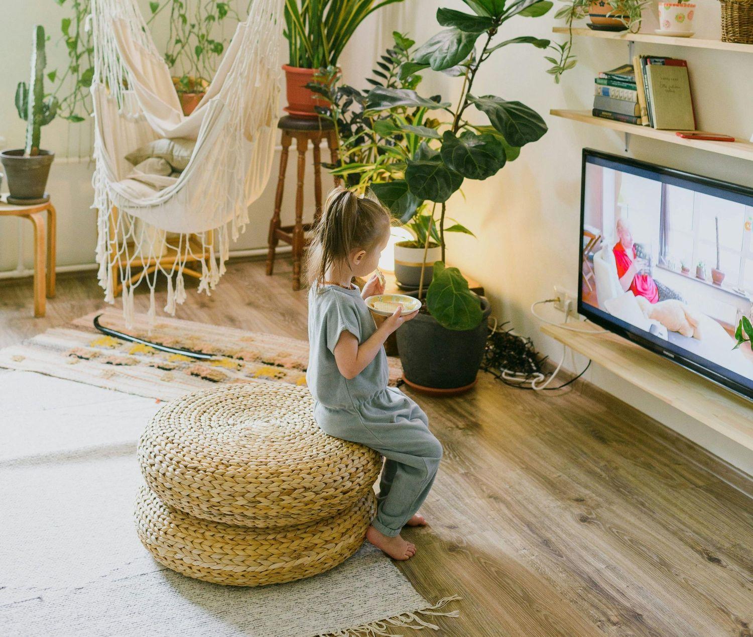 Ein Kind sitzt vor dem Fernseher und isst dabei etwas