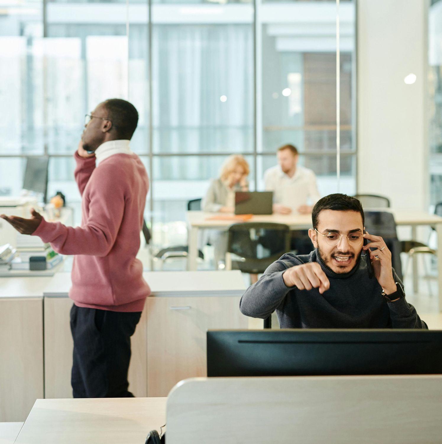 Männer sprechen laut am Telefon am Arbeitsplatz