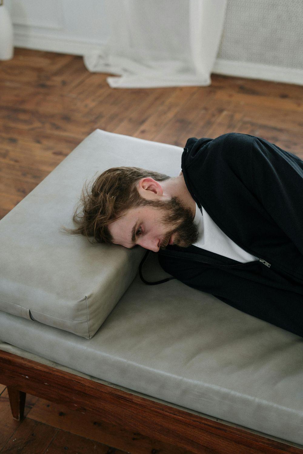 Ein Mann liegt auf einem Bett und leidet an Hyperakusis und Depressionen