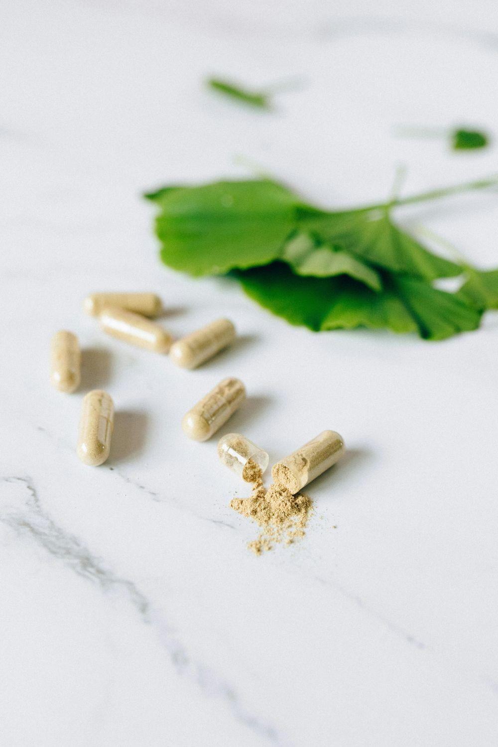 Nahaufnahme von Ginko Biloba Kapseln und Ginko Blättern, die das Hörvermögen verbessern sollen.